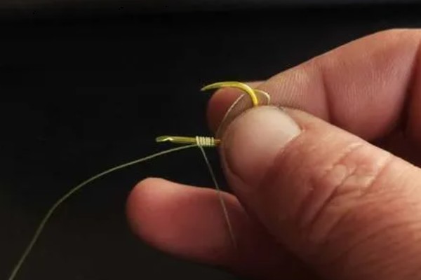 鱼钩怎样绑在鱼竿上，首先子线在钩柄中下部位置对折