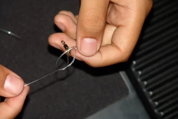 鱼钩怎样绑在鱼竿上，首先子线在钩柄中下部位置对折