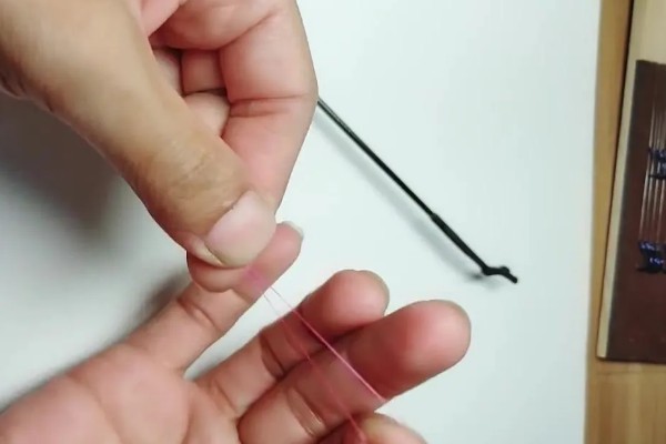 鱼钩怎样绑在鱼竿上，首先子线在钩柄中下部位置对折